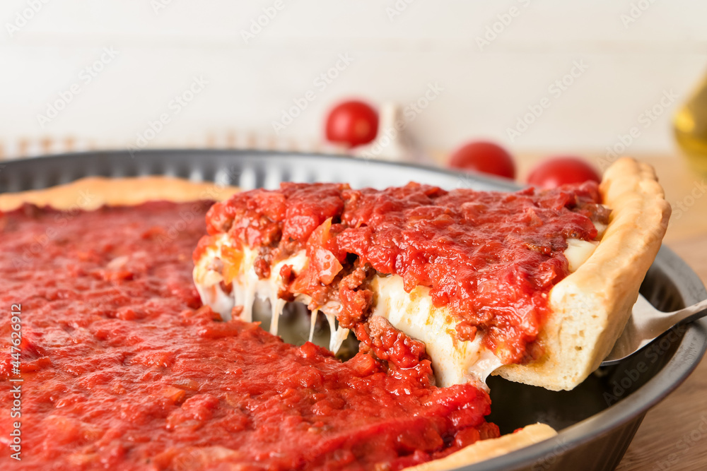 Baking dish with tasty Chicago-style pizza on light background, closeup