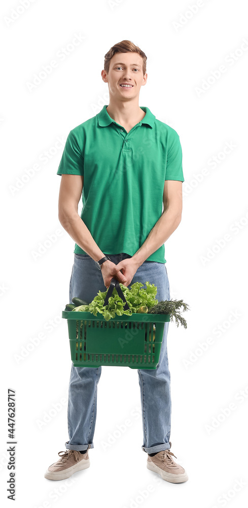 Young man holding shopping basket with fresh vegetables on white background