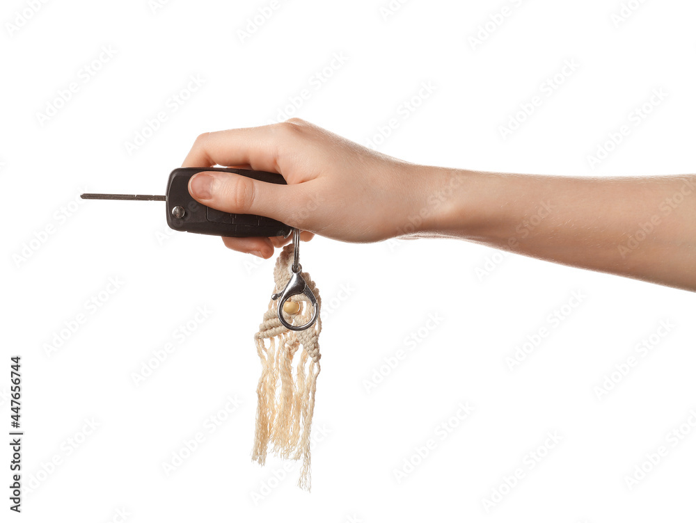 Female hand with car key and handmade cotton keychain on white background