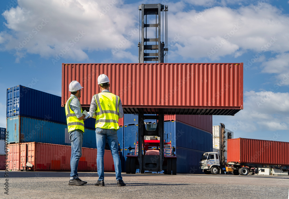 Engineers are overseeing the transportation of cargo with containers inside the warehouse. Container