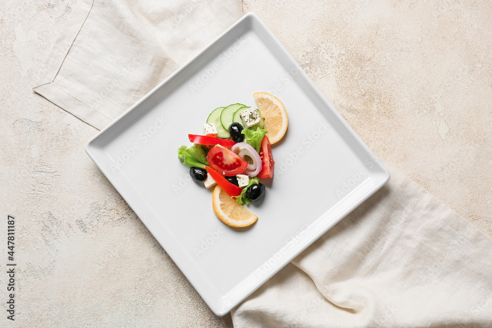 Plate with tasty Greek salad on light background