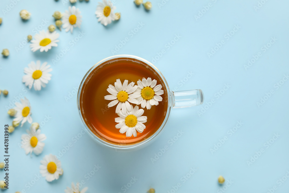 用一杯洋甘菊茶和彩色背景上的花朵组成