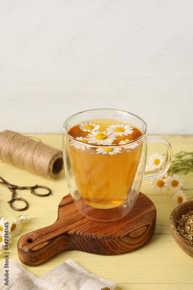 Composition with cup of chamomile tea and flowers on table