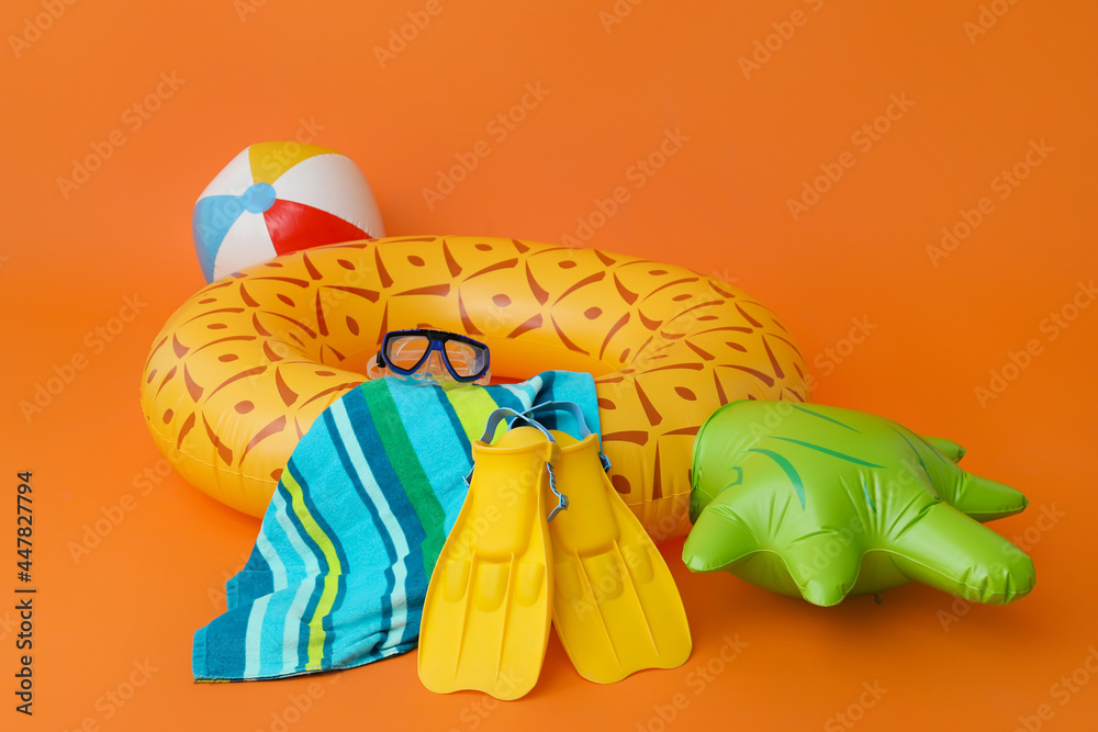 Inflatable ring, ball, towel, flippers and snorkeling mask on color background