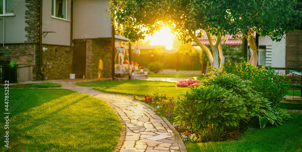 Beautiful manicured lawn and flowerbed with deciduous shrubs on private plot and track to house agai