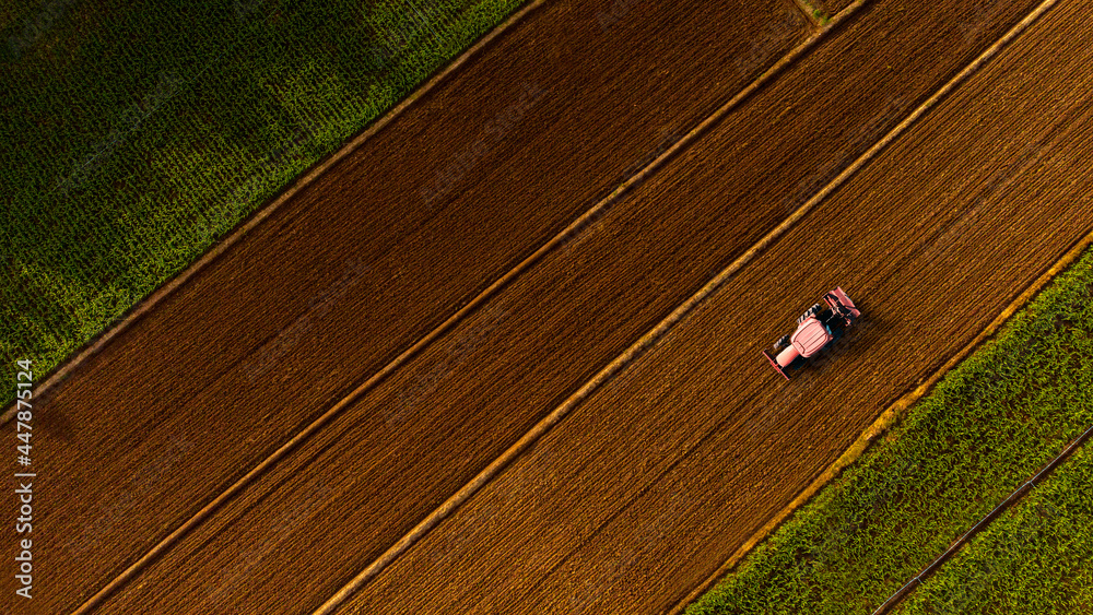 Aerial view over landscape of agricultural fields with tractor preparing farmland