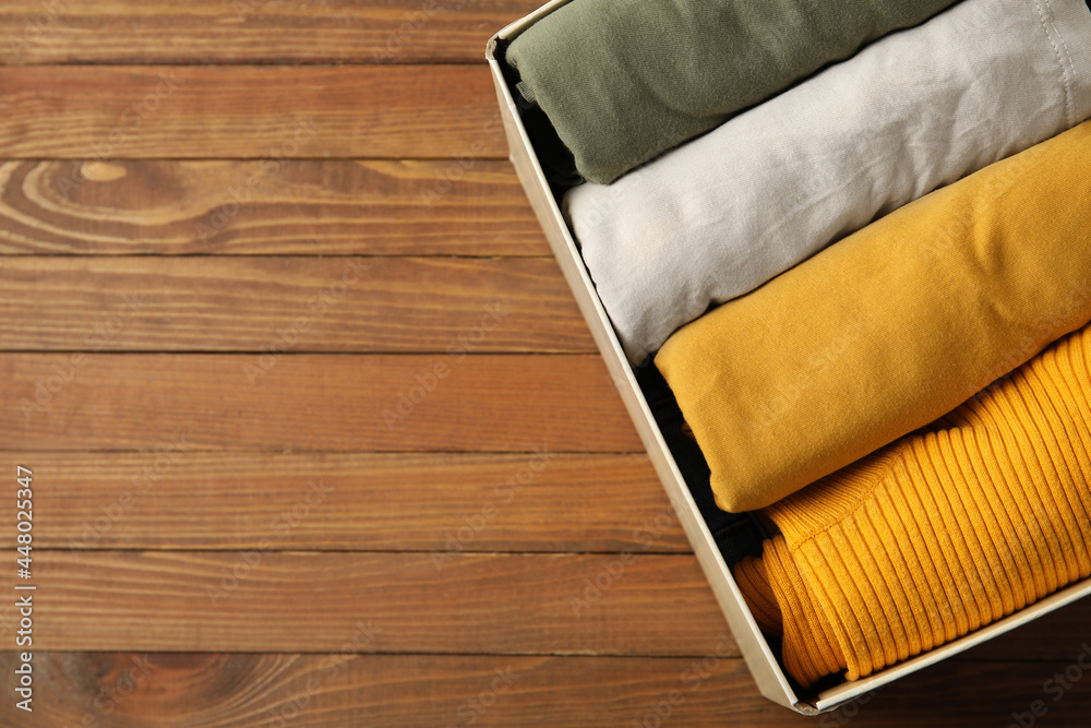 Wardrobe box with clothes on wooden background