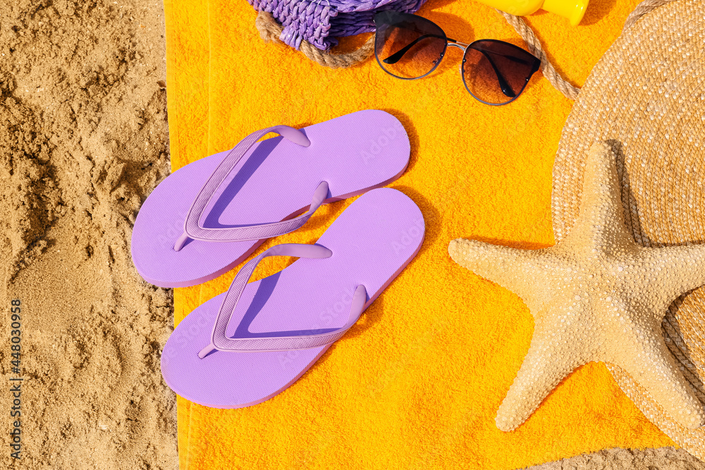 Stylish flip-flops and beach accessories on sand, closeup