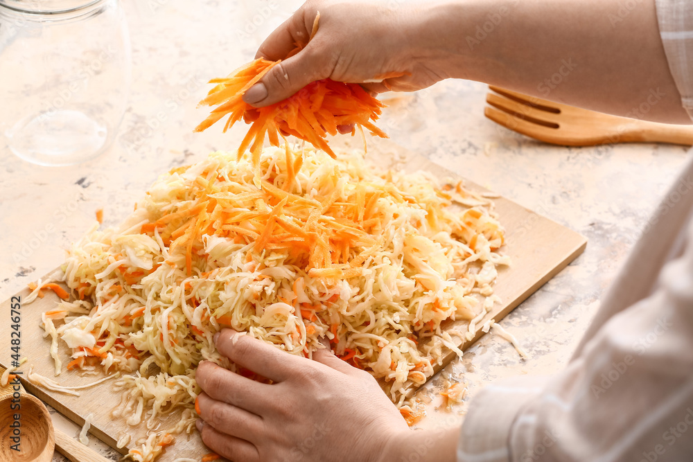 Woman preparing tasty sauerkraut at kitchen table, closeup