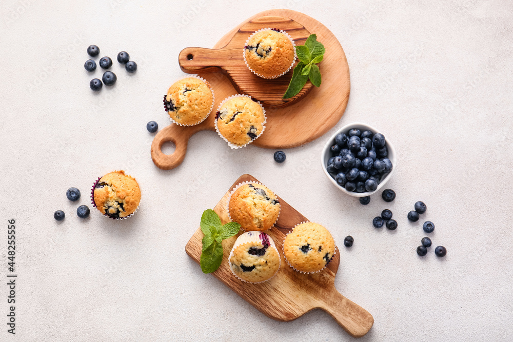 Composition with tasty blueberry muffins and berries on light background