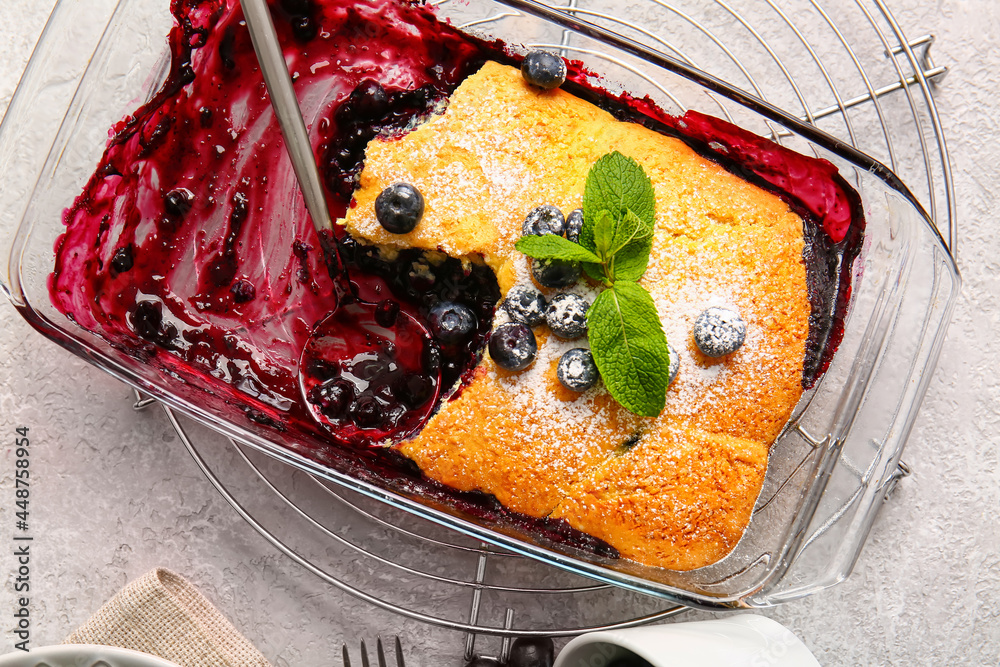 Baking dish with blueberry cobbler on light background