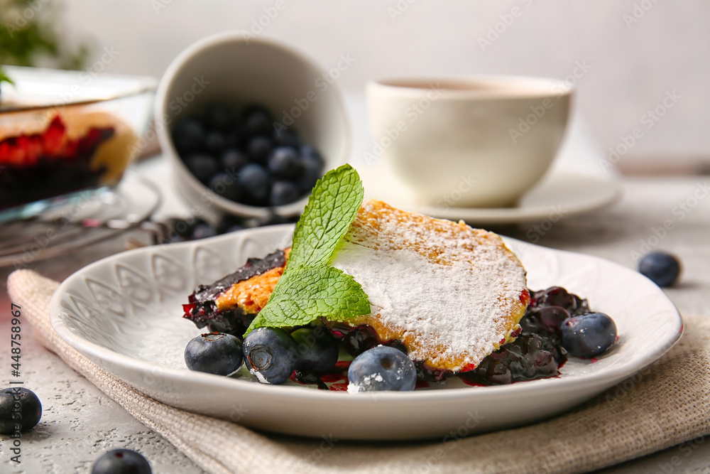 Plate with pieces of blueberry cobbler on light background, closeup