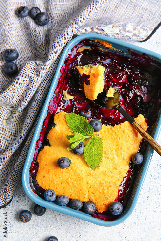 Baking dish with blueberry cobbler on light background