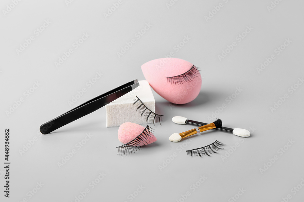 Composition with false eyelashes and tools on grey background