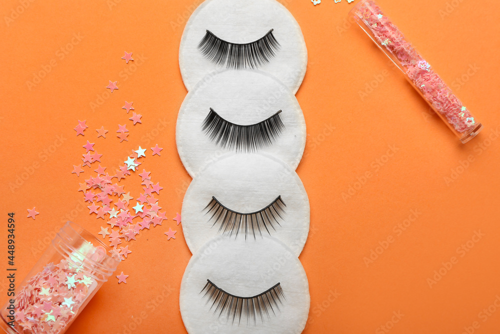 Composition with false eyelashes, cotton pads and glitters on color background