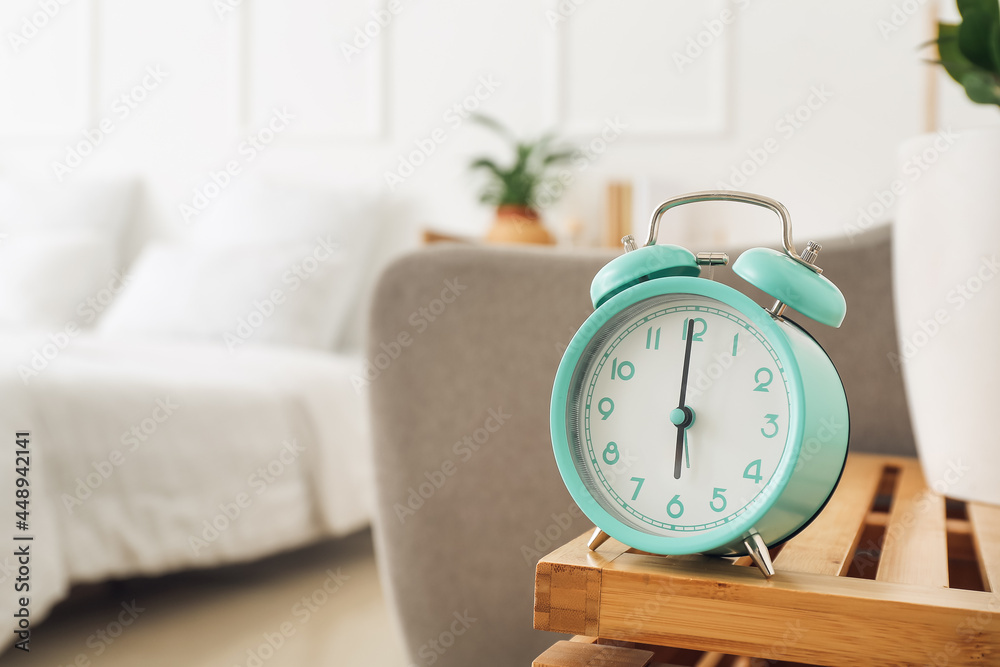 Stylish alarm clock on shelf in bedroom