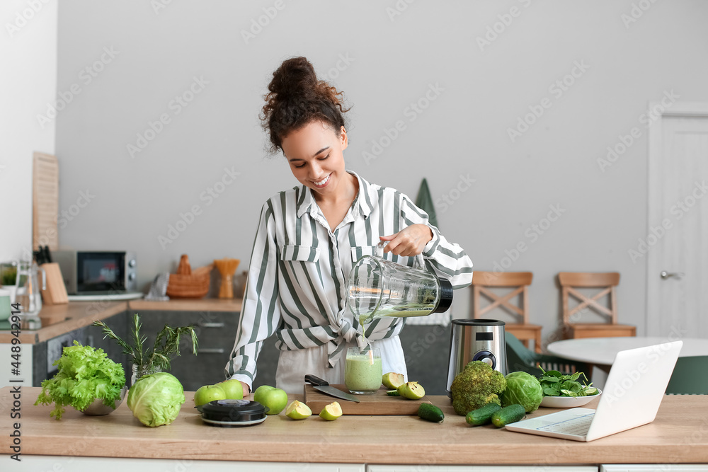 年轻的非裔美国妇女在厨房把新鲜的奶昔倒进杯子里