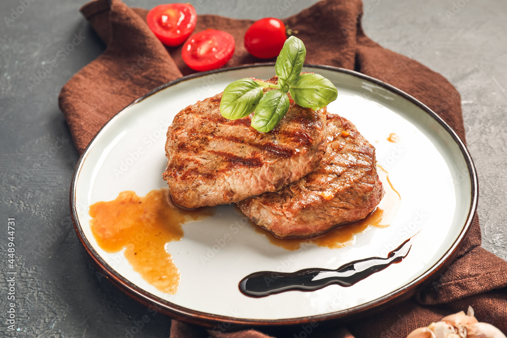 Plate with tasty beef steaks on dark background