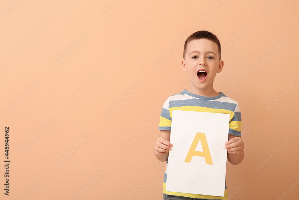 Little boy and paper sheet with letter A on color background