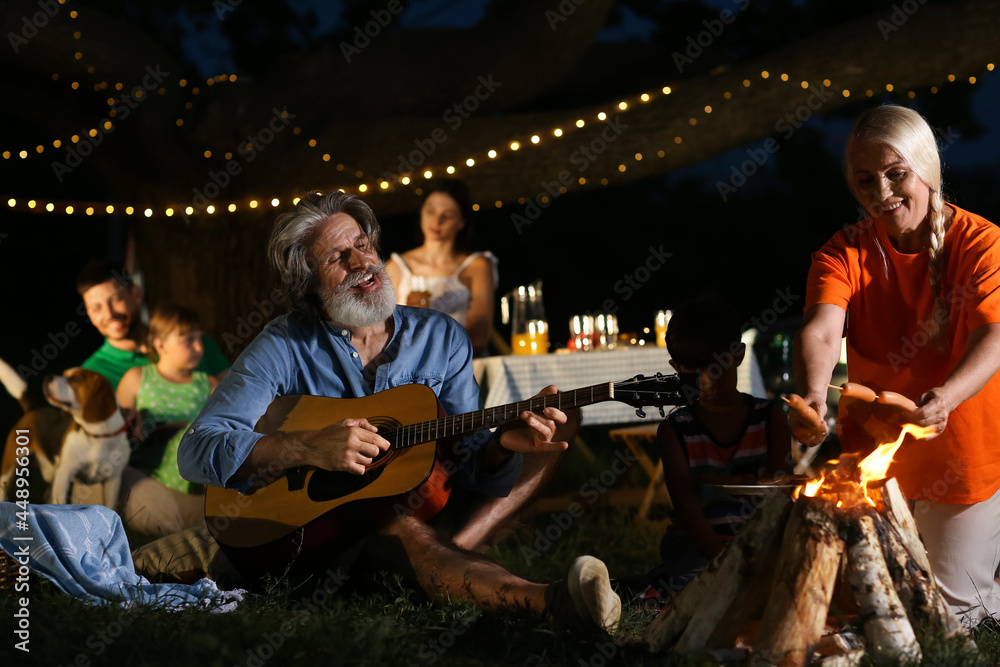 Happy family roasting sausages on fire outdoors