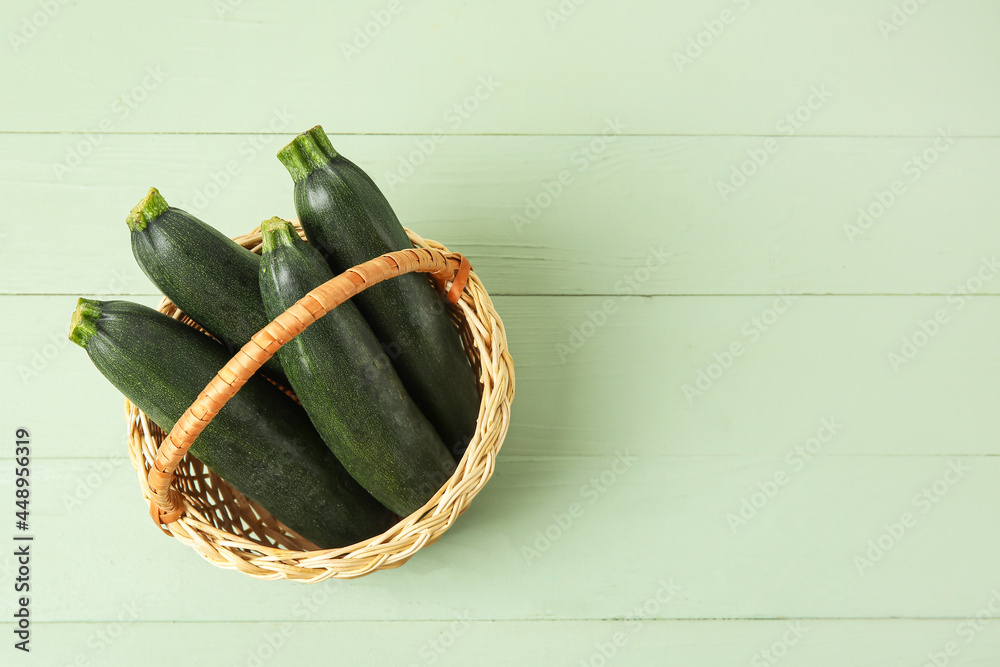 Basket with fresh zucchini squashes on color wooden background