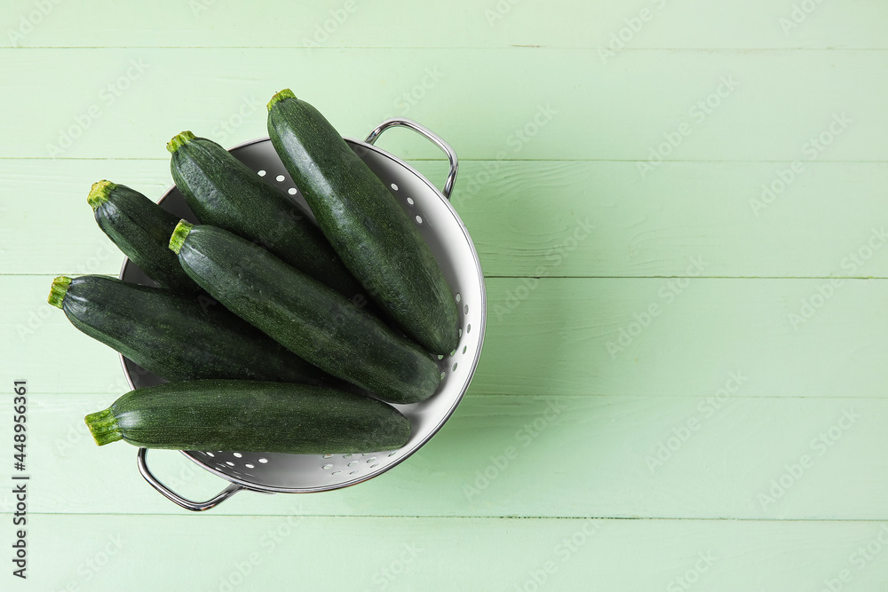 Colander with fresh zucchini squares on color wood background（彩色木质背景上的新鲜西葫芦南瓜香菜）