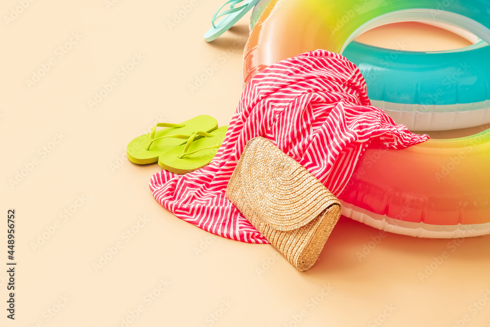 Inflatable rings, bag, dress and flip-flops on color background, closeup