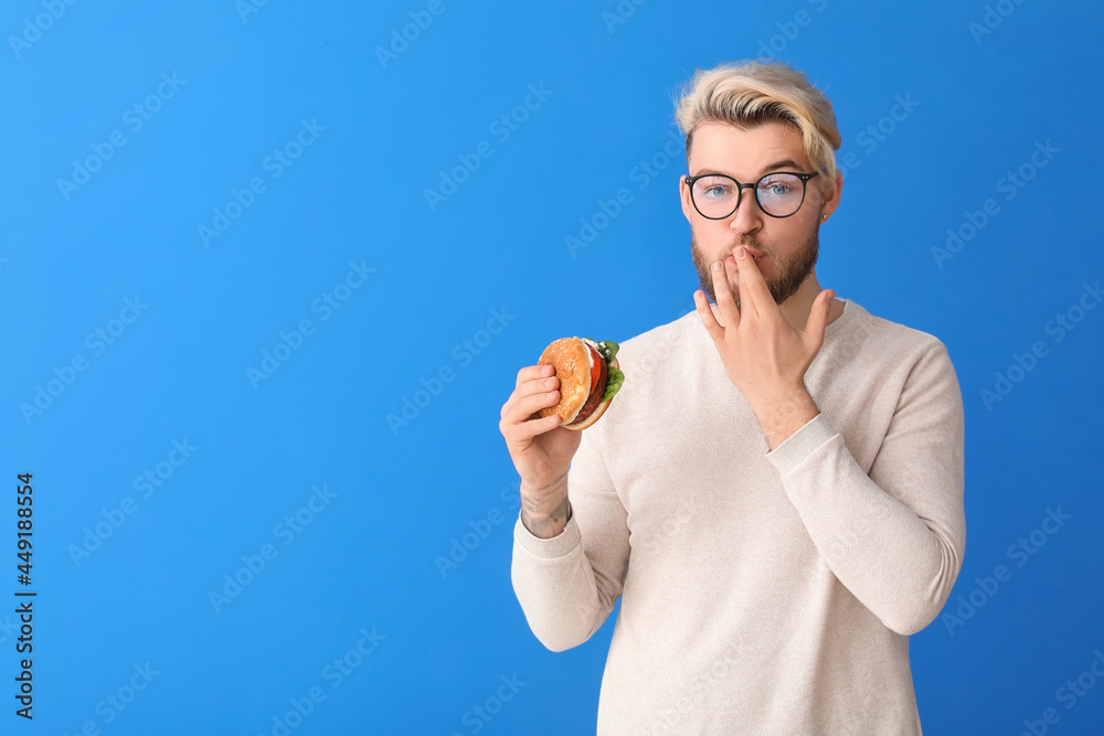 年轻人在彩色背景下吃纯素食汉堡