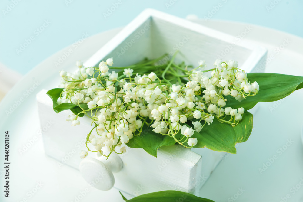 Box with lily-of-the-valley flowers on table, closeup