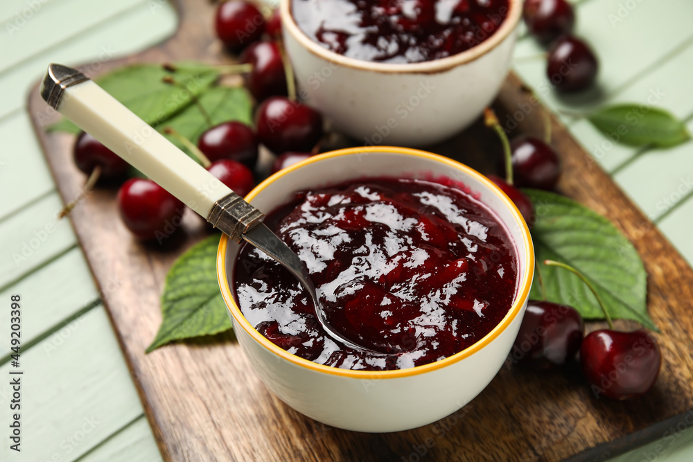 Bowl of tasty cherry jam on color wooden background