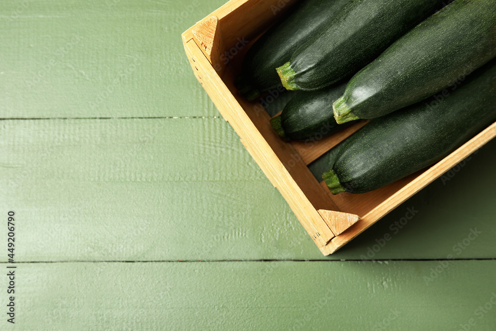 Wooden box with fresh zucchini squashes on color wooden background