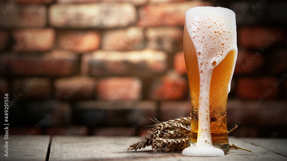 Glass of beer with foam spilling over the edge.