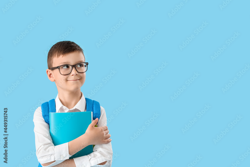 Little schoolboy with textbooks on color background