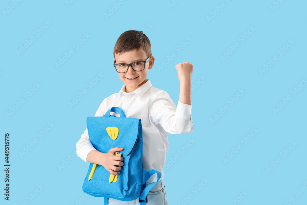 Happy little schoolboy with backpack on color background