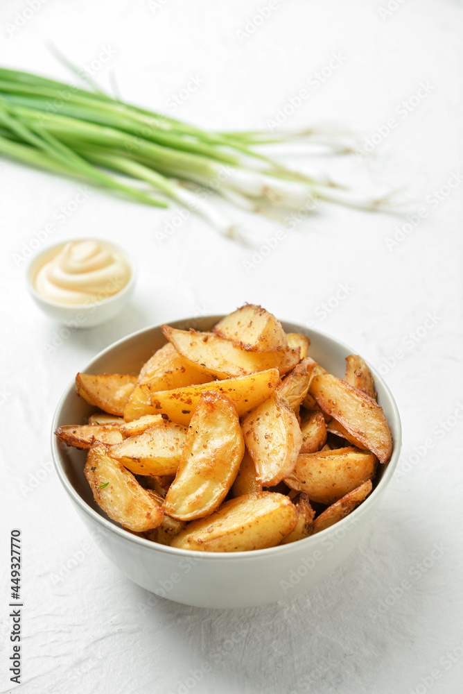 Bowl with tasty baked potato on light background