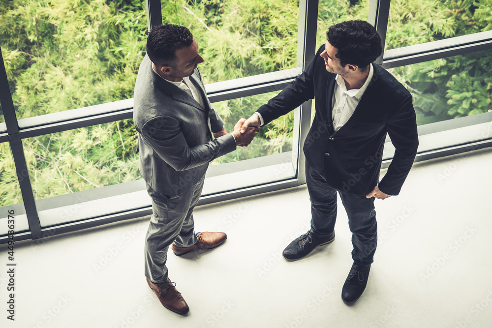 Businessman handshake with another businessman partner in modern workplace office. People corporate 