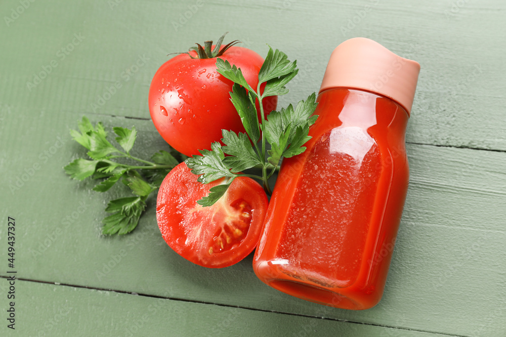 Bottle of tasty tomato juice on color wooden background