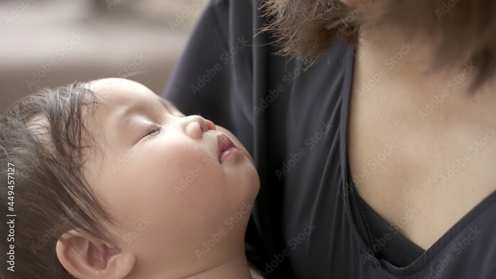 お昼寝する赤ちゃんを抱きかかえるお母さん