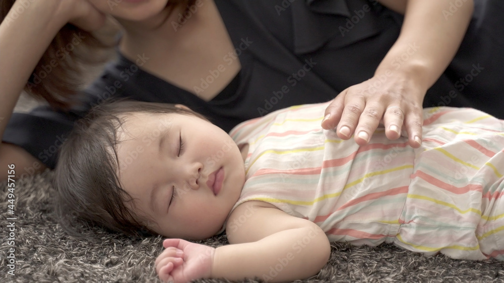 お昼寝する赤ちゃんを見守るお母さん