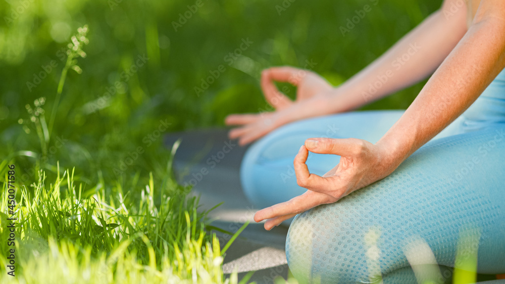 Young woman trainer in blue tracksuit meditates in yoga pose lotus holding hands on knees in legging