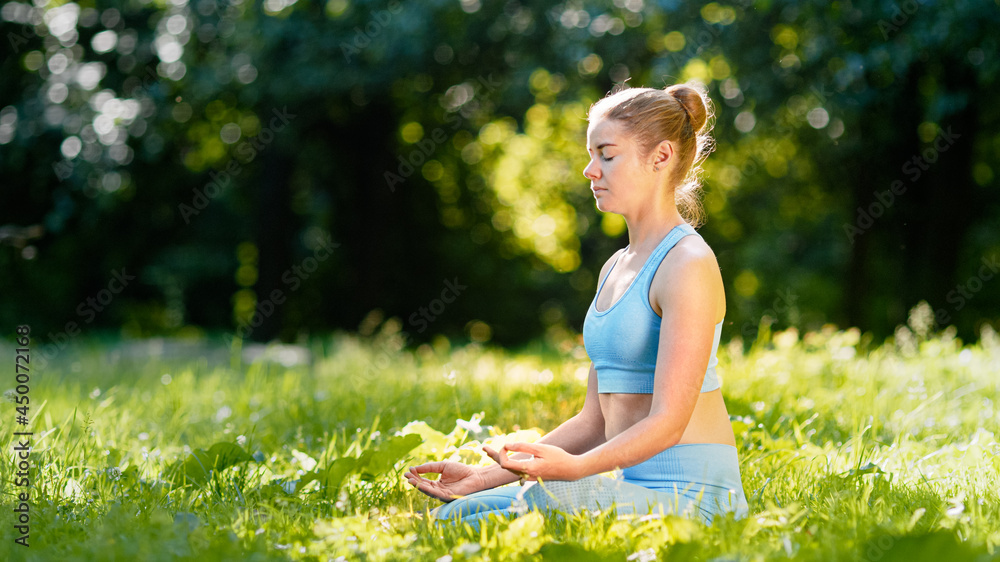 Lady athlete in blue tracksuit practices yoga sitting in relaxation pose