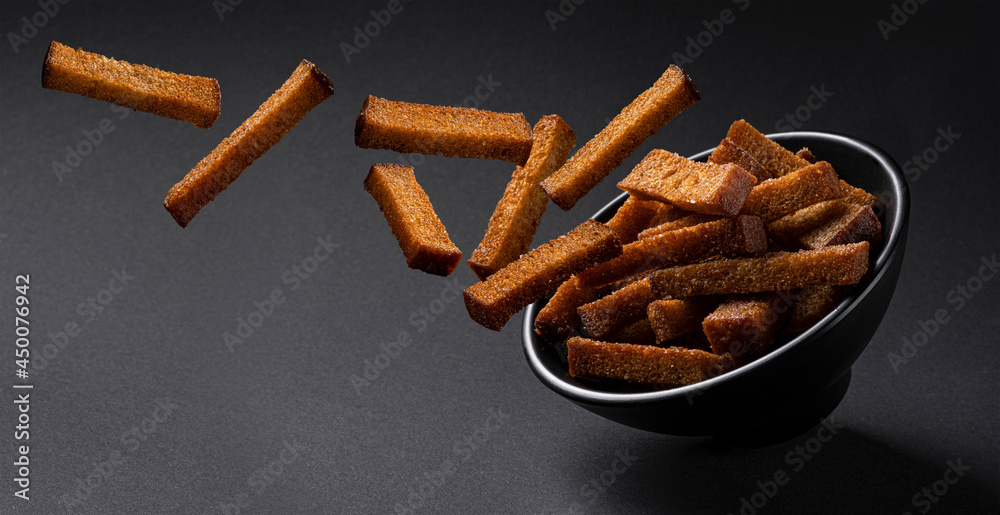 Falling rye croutons on black background