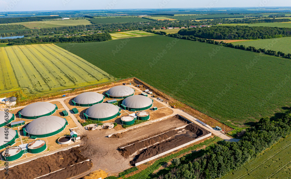 Biogas power station. Biogas plant for power generation and energy production around the green field