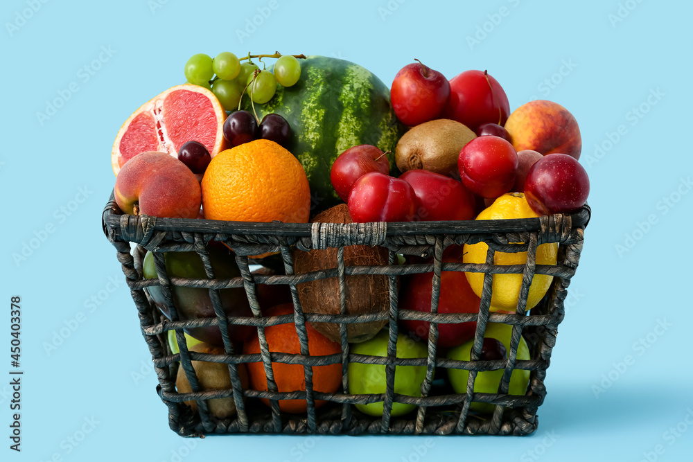 Basket with fresh fruits on color background