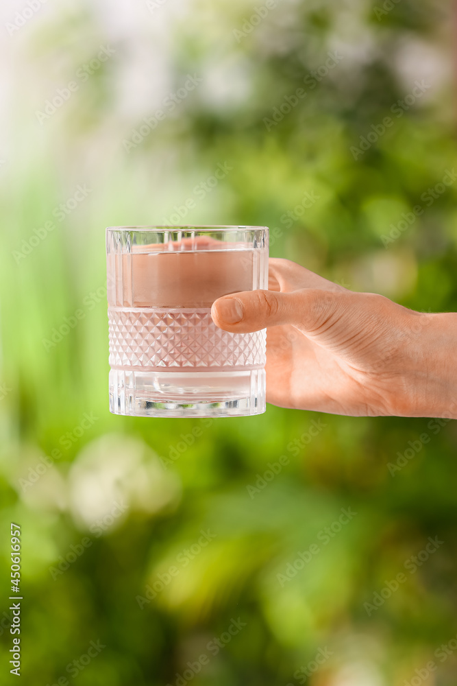 Female hand with glass of fresh cold water outdoors, closeup