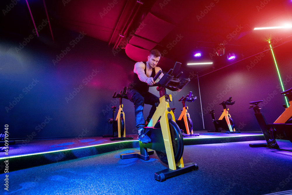 Handsome man training on a cycle at gym. Young active lifestyle adult man cycling.