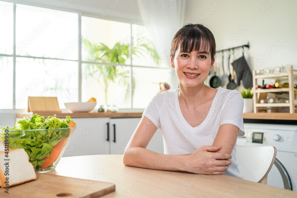 美丽成熟女人的画像，微笑着看着厨房里的相机