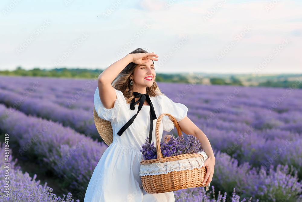 Beautiful young woman with basket in lavender field