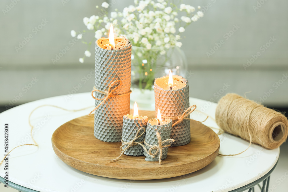 Wooden tray with burning candles and string cord rope on table in room