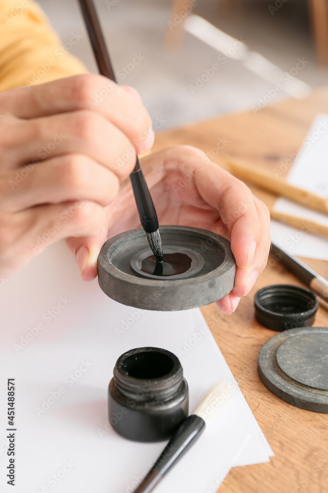 Young male calligrapher with ink at home, closeup